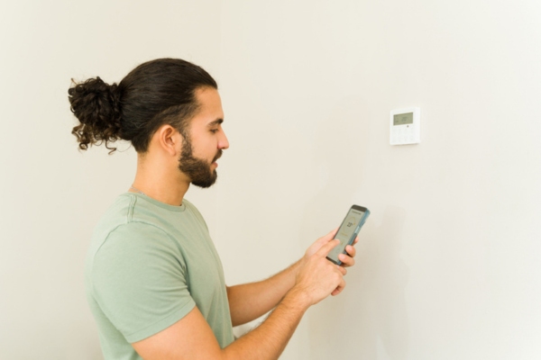 man exploring AC thermostat at home