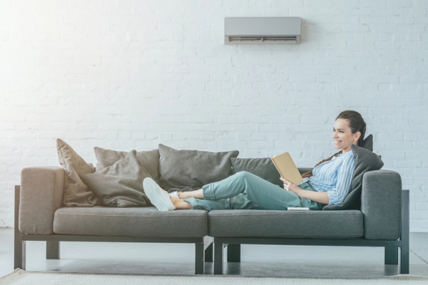 woman reading on the couch keeping cool with a ductless mini split air conditioner