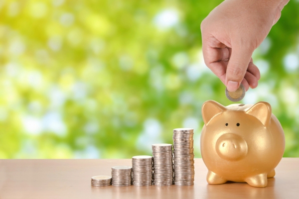 cropped photo of man's hand dropping coins on gold piggy bank depicting cost efficiency of propane