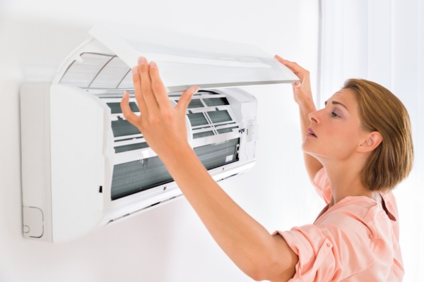 homeowner inspecting ductless air conditioner for mold growth