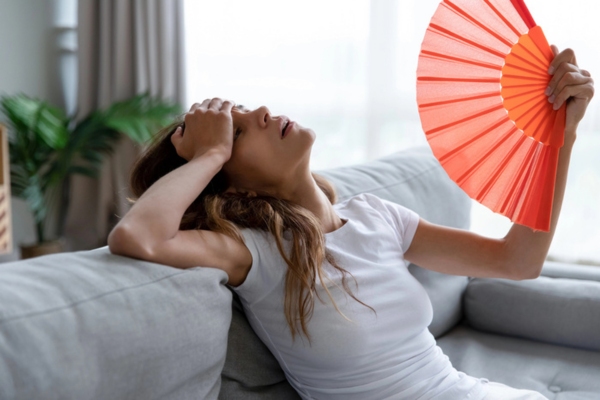woman feeling warm due to home air conditioner starts cold then gets warm