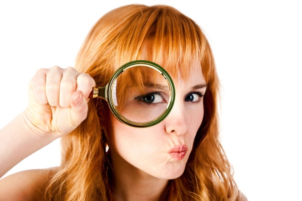 woman holding a magnifying glass on her eye depicting finding AC SEER rating