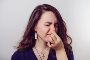 woman covers nose due to bad air conditioner smell