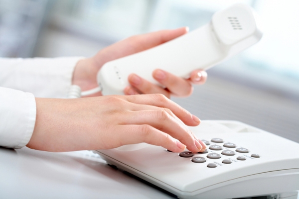 hands of a woman dialing on a landline depicting calling a professional furnace repair company