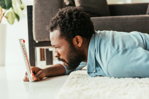 man looking at a thermometer depicting furnace overheating