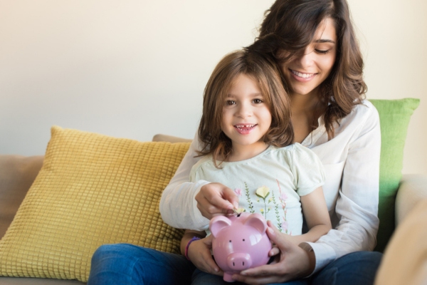 mom and child putting money in a piggy bank depicting cost effectiveness and heating system