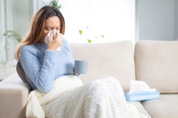 woman feeling sick while on the couch due to leaky HVAC ductwork