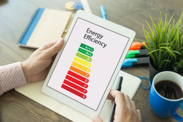 image of a person holding a digital tablet with energy efficiency meter displayed on the screen