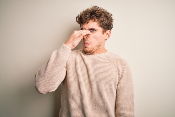 man covering nose due to bad smell caused by propane leaks